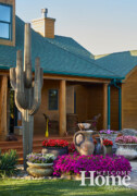 In the front of the home, large urns of flowers, boulders, and even a tall cactus welcome visitors. Photo by Jack Coyier, courtesy of Ted Lare Design + Build. Large urns of flowers, boulders, and a tall cactus by the covered front porch