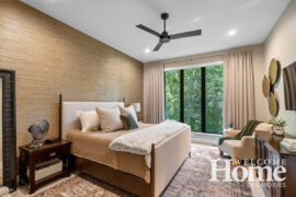 The primary suite uses grasscloth wallpaper on the headboard wall. Jill loves the textural aspects of the wallcovering. Note the huge tree behind the window.