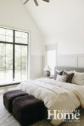 The main floor primary bedroom features a vaulted ceiling and large windows.