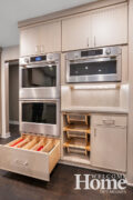 Cabinetry surrounds the double wall ovens and convection microwave, including vegetable baskets and large item storage.